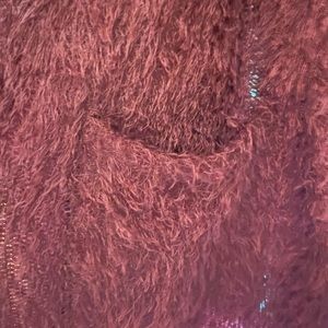 Burgundy jacket. Fuzzy material but not itchy, pockets, hits at hips.